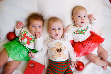 three babies are lying in a festive outfit on the background of new year and christmas decorations. The concept of holidays