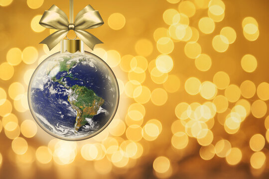 Christmas peace on earth goodwill to all concept showing glowing Xmas bauble with planet earth inside on golden bokeh background and copy space. Elements of this image furnished by NASA.