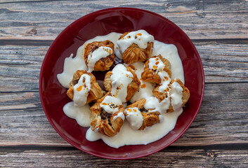 Ravioli made with puff pastry with yoghurt and tomato sauce on the plate; Turkish name (Sosyete ravioli)