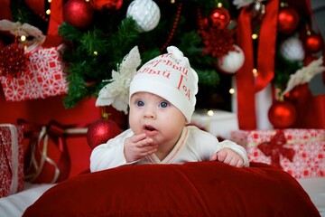 The baby lies in a festive outfit on the background of New Year and Christmas decorations. The concept of holidays