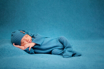 Niño recien nacido caucasico recostado de lado dormido en un fondo azul