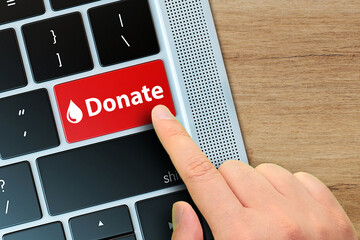 Blood Donation concept on computer keyboard. Human finger is pushing donate button on keyboard. 