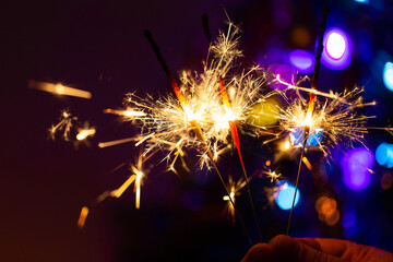 Burning sparklers glow in the dark. Stock photo of bright sparks in close-up. Christmas holiday mood. - 544433164