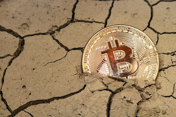 bitcoin in the form of a coin lies on dry cracked ground