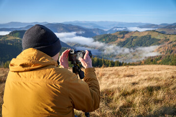 A young photographer taking picturesque photos using proffesional camera. Landscape photography. Content maker. Pro photographer. The concept of travel and active lifestyle