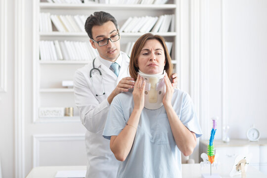 Male doctor orthopedist explaining to his female patient with serious neck injury in neck brace about importance of cervical collar for healthy cure