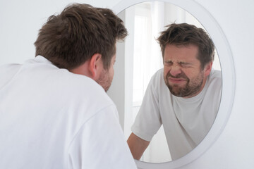 Fototapeta premium Tired mature caucasian man is looking at the mirror.