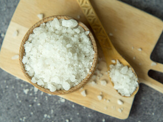 sea crystal salt in a wooden bowl and spoon on a wooden board