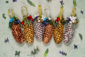 Decorated Christmas tree toys in a rural style. Golden pine cones with glued leaves, berries, beads, ribbons, top view - 544437730