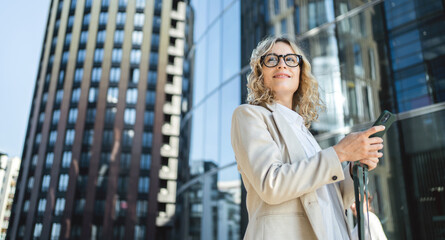 A woman with glasses is a marketing expert working in an office. Uses a phone device in his hands, communicating with a colleague.