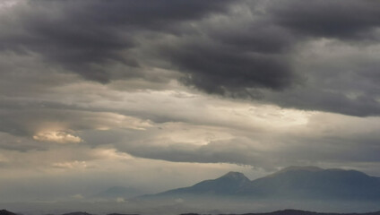 Fototapeta na wymiar Monti Appennini avvolti di nebbie e nuvole e chiarori di sole