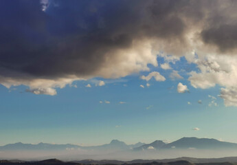 Nuvole bianche e nuvole nere nel cielo azzurro sopra i monti Appennini
