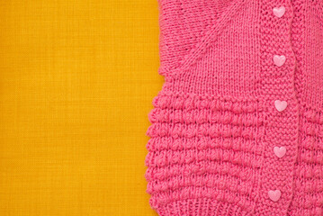handmade children pink sweater with heart shaped buttons on a yellow background, made with love - obrazy, fototapety, plakaty