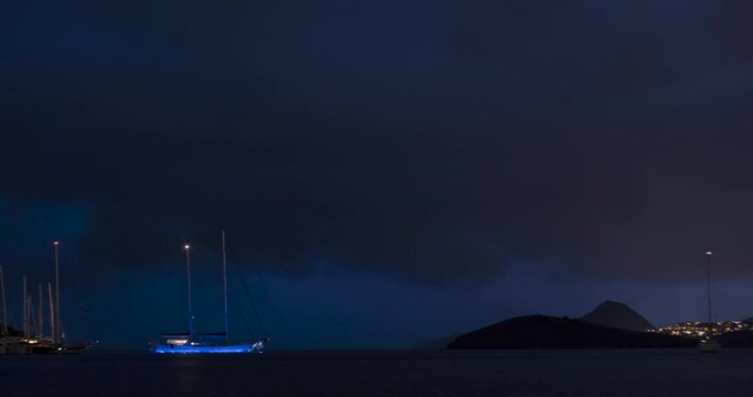 Timelapse of supercell storm approaching shore at night, lightnings, boats and beach Bitez, Bodrum