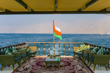 Oman Flag on a boat with sea and mountain backgrounds 