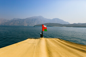 Oman Flag on a boat with sea and mountain backgrounds 