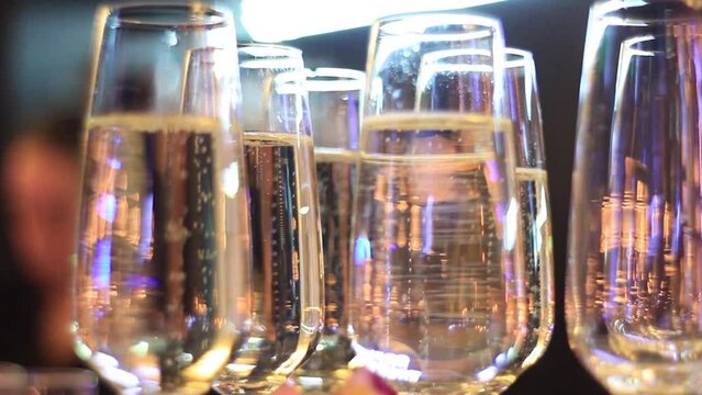 Set of crystal wineglasses hangs on stand with upper illumination in restaurant.