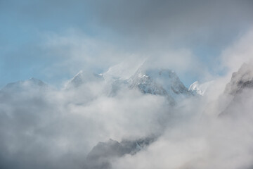 Beautiful snow castle in low clouds. Lovely scenery with high snowy mountains in thick clouds. Big...
