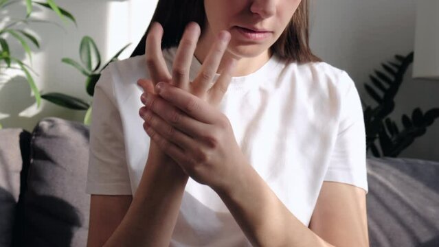 Close up of female suffer from numbing pain in hand, numbness fingertip, arthritis inflammation, peripheral neuropathies, sad young woman massage hand with wrist pain, rheumatoid arthritis concept