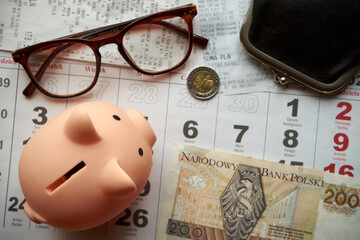 paragony fiskalne ,polskie banknoty , polska moneta, kartka z kalendarza, świnka skarbonka, emerytura	