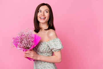 Photo of adorable thoughtful lady wear green clothes smiling looking empty space holding baby breath flower isolated pink color background