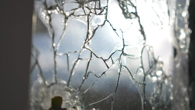 Close-up wrecked glass in sunrays outdoors. Destroyed demolished window in Ukraine Kiev on sunny day. Bombardment and air raid consequences