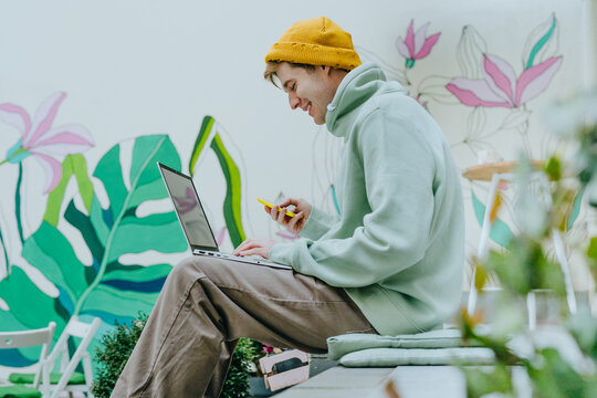 Freelancer young man working on laptop sitting on the stairs