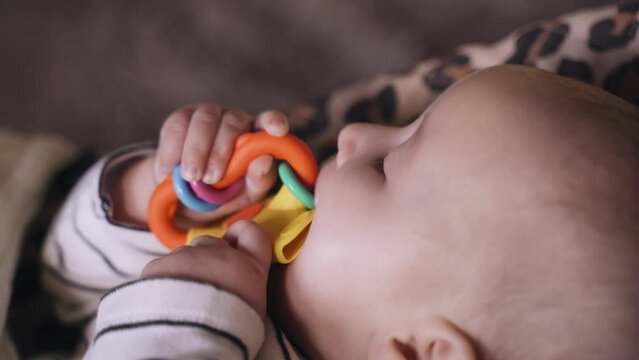 Portrait of a small child chewing on a teether toy. The concept of teething in a child.