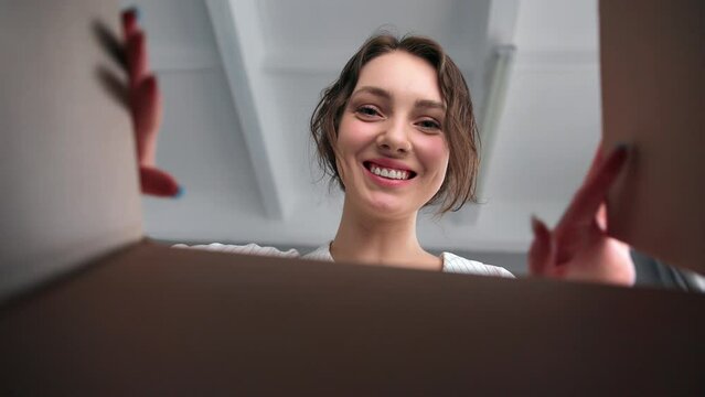 Cute female open cardboard box unpacking parcel marketplace order delivery positive emotion POV shot