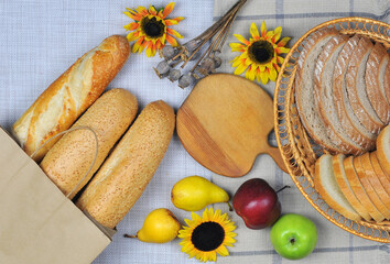 Different kinds of fresh crusty bread with fruits on the table top view. Long french baguette and...