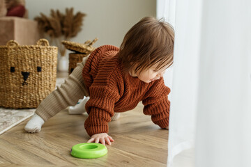 Toddler child is playing with toys on floor in room. Childhood, kindergarten and development concept