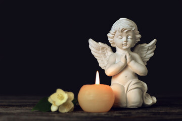 Sympathy card. Angel, funeral flower and candle on black background with copy space