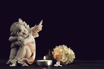 Condolence card. Angel, funeral flower and candle on black background with copy space