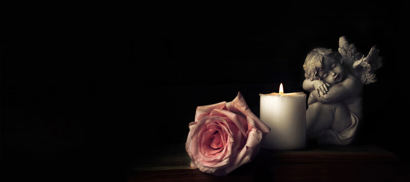 Sympathy card. Angel, funeral flower and candle on black background with copy space