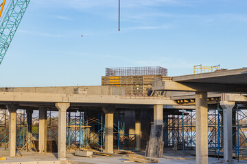 Crane and building under construction against blue sky on lake bank. Urban landscape