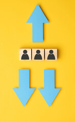 Wooden cubes with arrows in opposite directions on a yellow background. Concept of thinking...