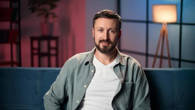 Portrait handsome man relaxing evening home cosiness lighting interior posing sitting on couch