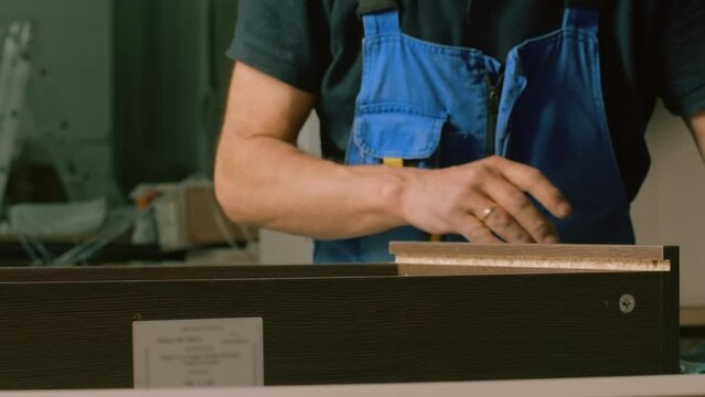 Construction process. Creative. Men in special clothes with perforated boards and boards are trying to assemble furniture.