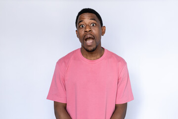 Portrait of surprised African American man. Shocked young male model with short dark hair in pink T-shirt looking at camera with open mouth, reacting to news. Shock concept