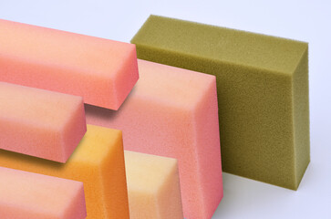 square pieces of thick spongy foam in brown, pink, cream and orange colors on a white background. a...