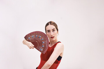 A girl in a red top and a black skirt with a fan in her hands dances a passionate Spanish flamenco dance. Artistic movements, emotions, the ability to keep yourself on stage. A charming woman. - obrazy, fototapety, plakaty