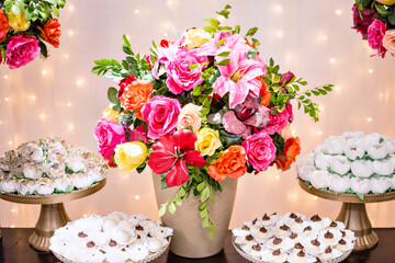 Chocolate candies on the table and a vase of colorful flowers in the center