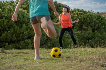 Two 30s years old woman training to play soccer or European football in amateur team. Yellow ball, sport field with green grass.