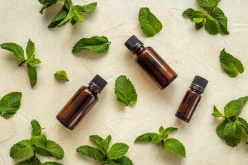 Fototapeta na wymiar Bottle of essential peppermint oil with fresh green mint leaves