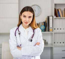 Cheerful smiling female doctor physician standing in medical clinic with clipboard. Medicine concept