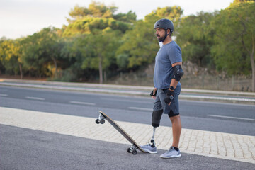 Side view of determined person with disability on skateboard. Caucasian man with mechanical leg in helmet skateboarding in park on sunny day. Sport, disability concept