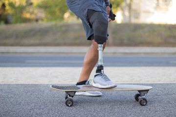 Close-up of man with prosthetic leg riding skateboard. Strong person with disability in casual...