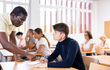 Fototapeta premium African american teacher prompts an adult student to solve the equation