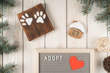 Art creative composition of wooden board with two animal paws, house model and adopt board with fir tree twig decoration