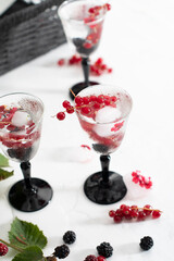 transparent gin and tonic with ice and fresh red currants and blackberries 